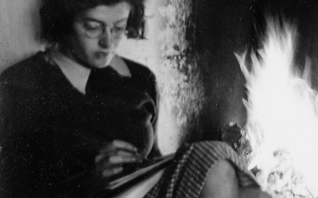 historisches Foto: Ruth Maier lesend. Hintergrund Kaminfeuer