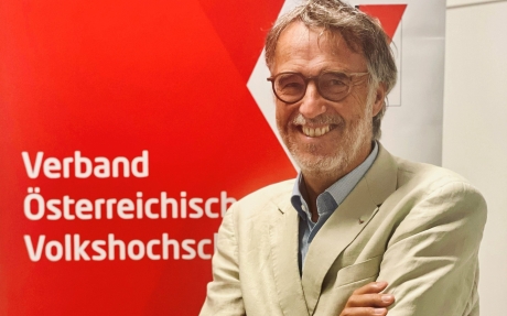 Gerwin Müller vor der Fotowand des Verband Österreichische Volkshochschulen