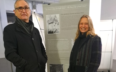 Foto mit Karl Ramsmaier und Monika Sträußlberger vor einem Plakat der Ausstellung.