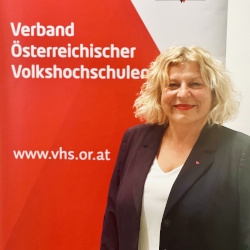 Beate Gfrerer vor der Fotowand des Verband Österreichische Volkshochschulen