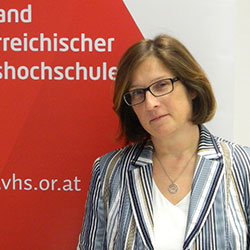 Ingrid Hammer vor der Fotowand des Verband Österreichische Volkshochschulen